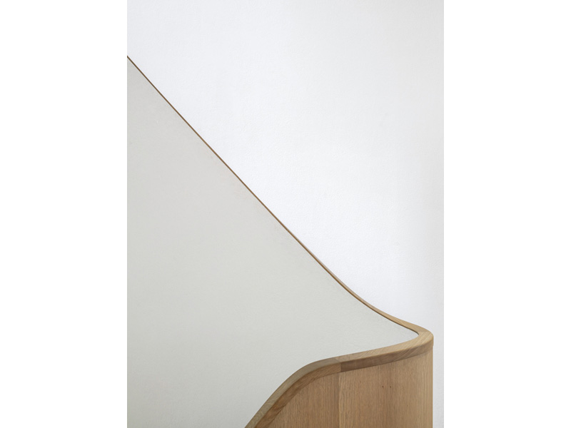 Solid oak handrail and matching balustrade with an internal face of oak veneer and a polished plaster exterior (318.studio)
